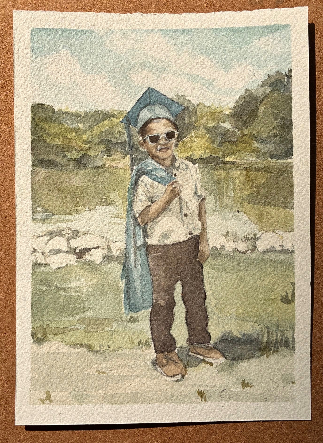 watercolor painting with a young boy in a graduation cap with his gown over his shoulder