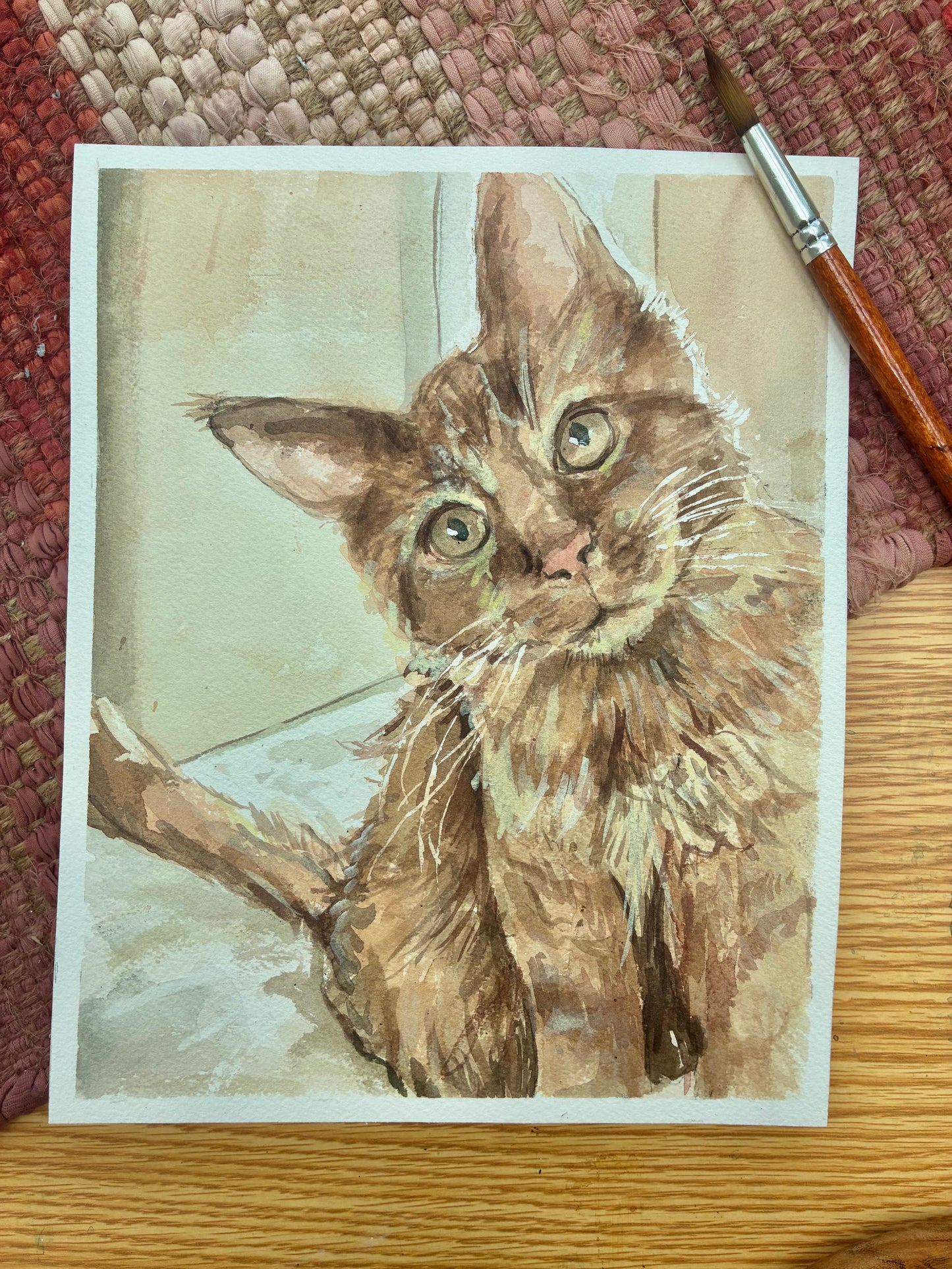 This is a watercolor painting of an orange cat with green eyes
