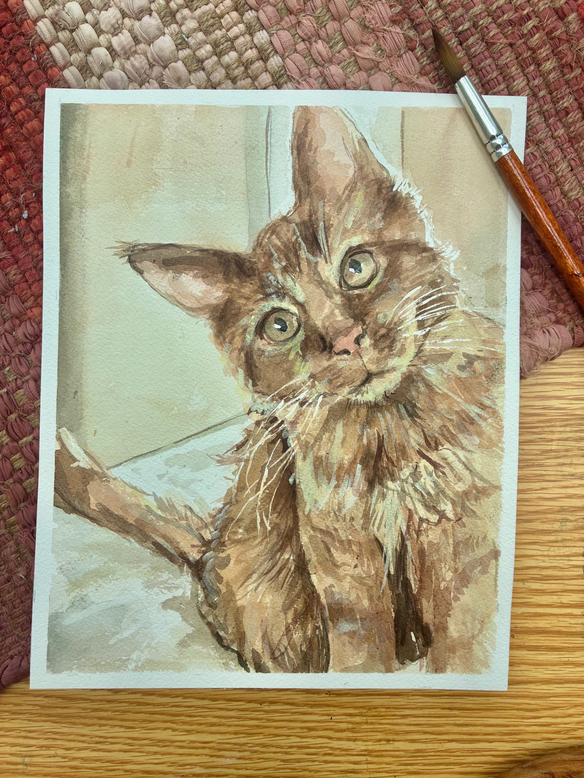 This is a watercolor painting of an orange cat with green eyes